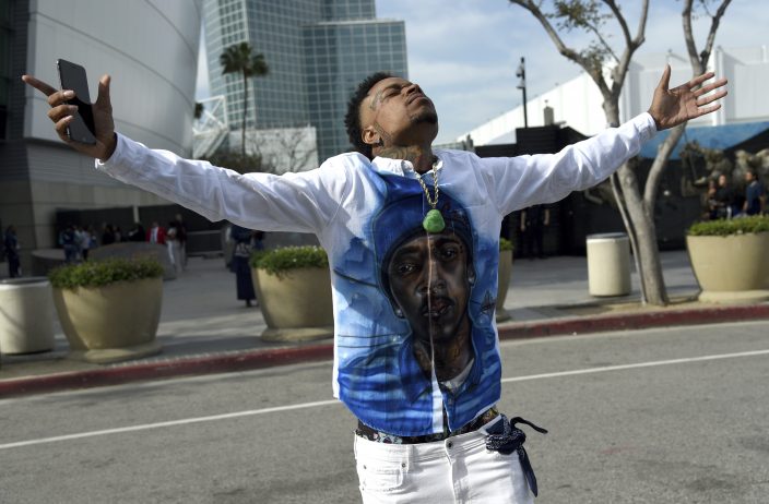 A fan of rapper Nipsey Hussle holds a sign as he attends a public